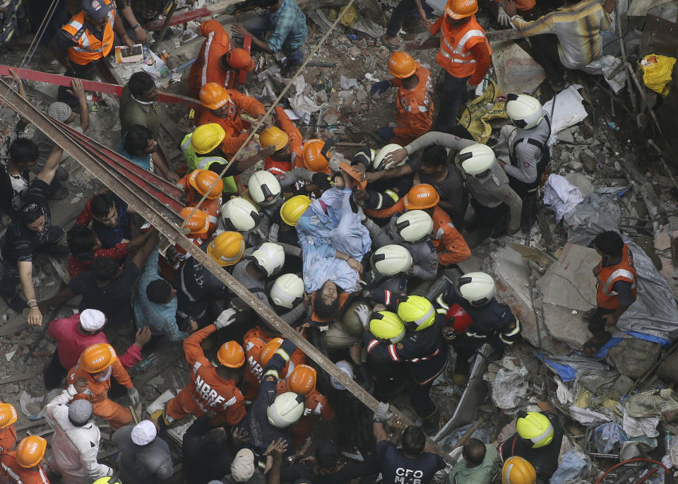 Rescuers carry out a survivor from the site of a building that collapsed in Mumbai, India, Tuesday, July 16, 2019. A four-story residential building collapsed Tuesday in a crowded neighborhood in Mumbai, India's financial and entertainment capital, and several people were feared trapped in the rubble, an official said.(AP Photo/Rajanish Kakade)