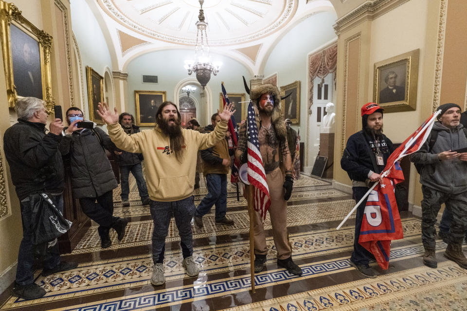 FILE - In this Wednesday, Jan. 6, 2021 file photo, supporters of President Donald Trump are confronted by U.S. Capitol Police officers outside the Senate Chamber inside the Capitol in Washington. On Friday, Jan. 8, 2021, The Associated Press reported on stories circulating online incorrectly asserting that Capitol rioters were antifa activists. At center is Jake Angeli, wearing fur hat with horns, a regular at pro-Trump events and a known follower of QAnon. (AP Photo/Manuel Balce Ceneta)