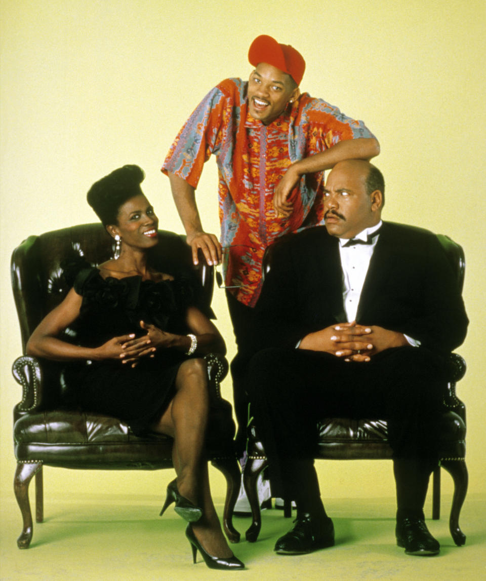 Three characters from "The Fresh Prince of Bel-Air" in a promotional photo, posing humorously with one standing, one seated, and one leaning