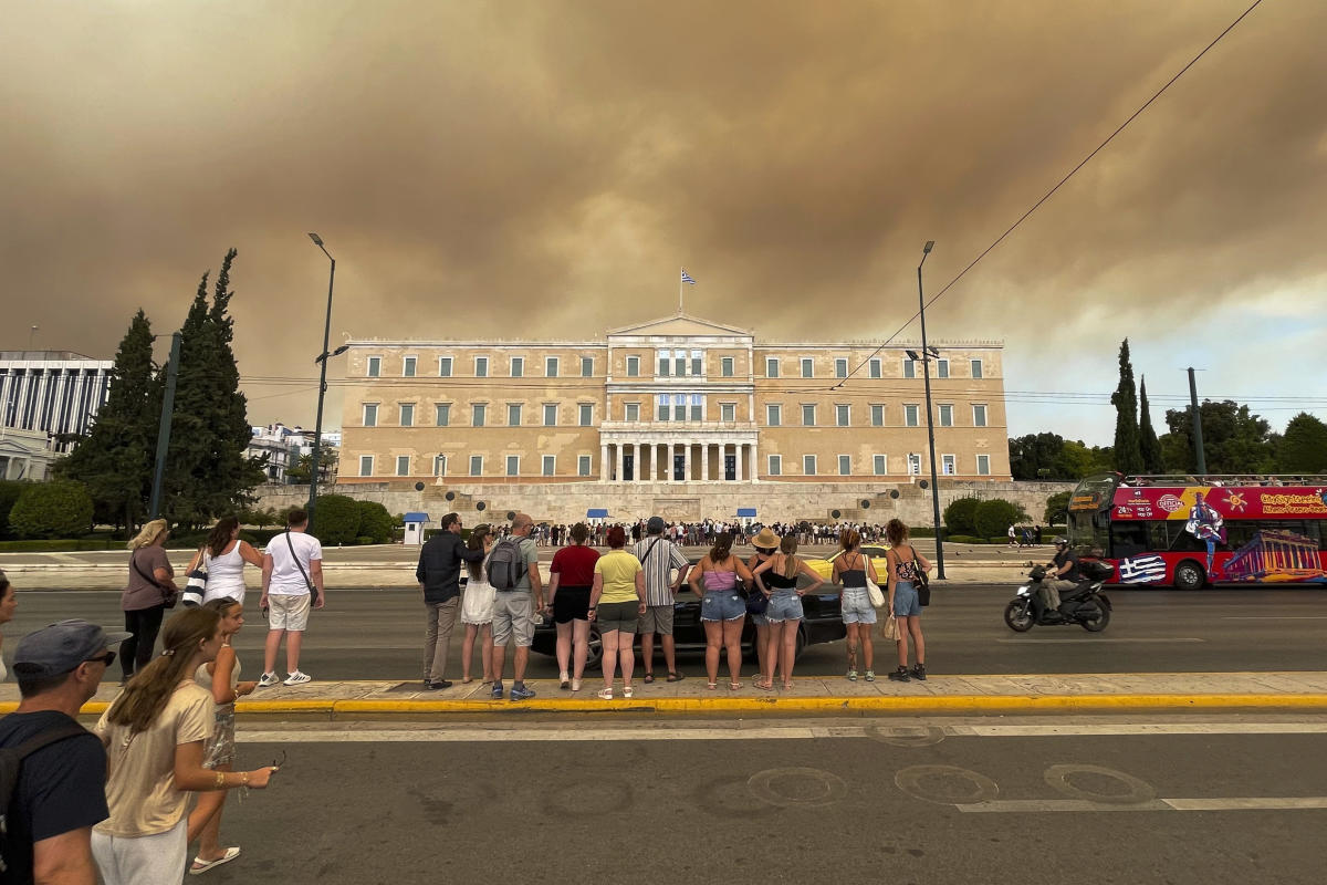 A forest fire near the Greek capital darkens the skies over Athens and spreads rapidly