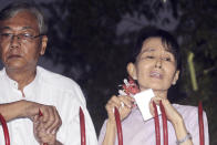 FILE - Myanmar's pro-democracy leader Aung San Suu Kyi, right, stands with aide Htin Kyaw, as she addresses her supporters from her front gate after her release from house arrest in Yangon, Myanmar, on Nov. 13, 2010. The Myanmar opposition leader was in house arrest for participating in anti-government protests when she was awarded the 1991 Nobel Peace Prize. (AP Photo, File)