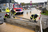 Firefighters set up a flood barrier in Gromitz, Germany, Friday Oct. 20, 2023. Due to a storm low, roads and shore areas on the Baltic Sea coast have been flooded by high water. A severe storm surge is expected in the north for the rest of the day. (Daniel Bockwoldt/dpa via AP)