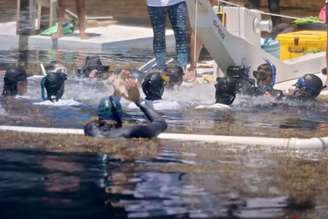 <p>Peacock</p> Divers cheer for Bloom after he makes his way safely back to the surface.