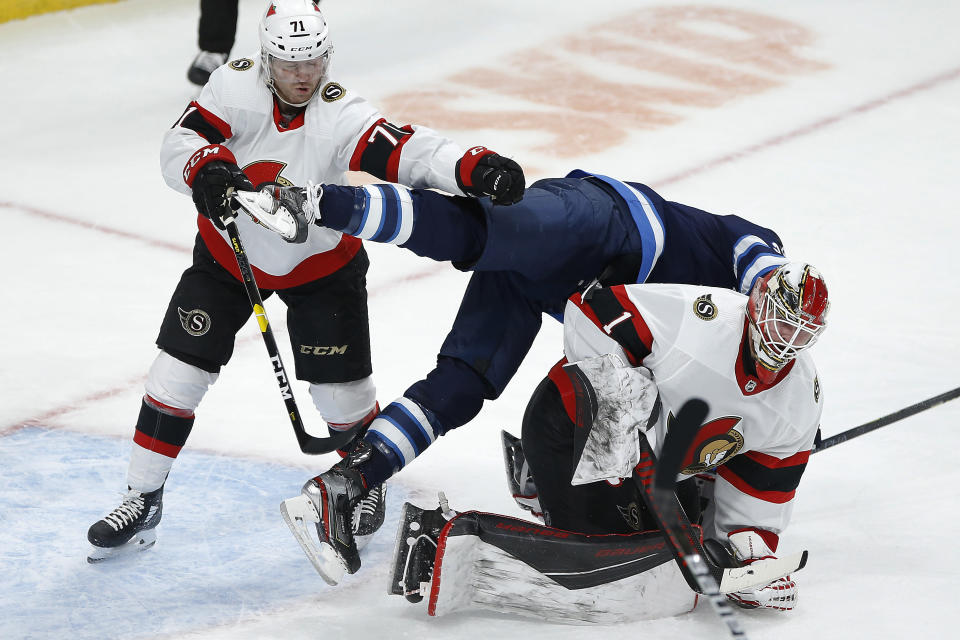 Winnipeg Jets' Blake Wheeler (26) gets pushed over the back of Ottawa Senators goaltender Marcus Hogberg (1) by Chris Tierney (71) during the third period of an NHL hockey game Saturday, Jan. 23, 2021, in Winnipeg, Manitoba. (John Woods/The Canadian Press via AP)