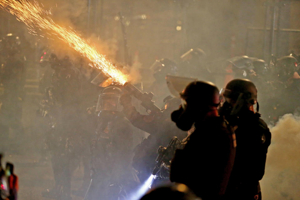 Portland protests return downtown as police use tear gas early Thursday, Aug. 13, 2020. Officers used tear gas to break up the crowd of several hundred people who gathered near the Mark O. Hatfield U.S. Courthouse, the neighboring Multnomah County Justice Center and a nearby police precinct station. (Sean Meagher/The Oregonian via AP)