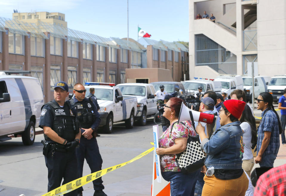 Immigration rights activists, right, protest as Customs and Border Patrol agents stand at the port of entry after Cardinal Sean O'Malley, leader of the Boston Archdiocese, led mass, Tuesday, April 1, 2014, in Nogales, Ariz. A delegation of Roman Catholic leaders celebrated Mass along the U.S.-Mexico border to raise awareness about immigration and to pray for policy changes. (AP Photo/Matt York)