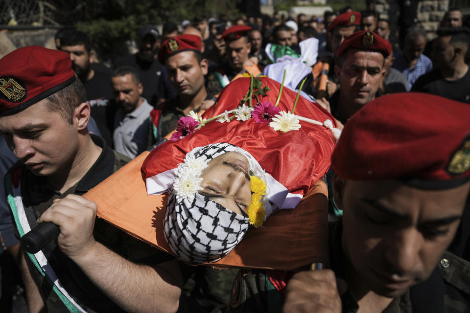 A Palestinian honor guard carries the body of Qusai Matan, 19, during his funeral in the West Bank city of Ramallah, Saturday, Aug. 5, 2023. On Friday the Palestinian Health Ministry said that armed Israeli settlers had entered the West Bank village of Burqa and shot and killed 19-year-old Qusai Matan. The Israeli military said it had received reports that Matan died as a result of settlers shooting toward Palestinians in the village and said it's investigating. (AP Photo/Nasser Nasser)
