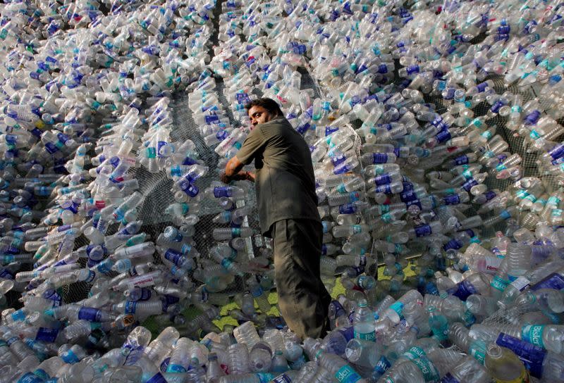 FILE PHOTO: An employee of Mumbai Educational Trust (MET), which runs educational institutes, adjusts plastic bottles in an installation made of approximately 40,000 plastic bottles to protest the use of plastic, in Mumbai