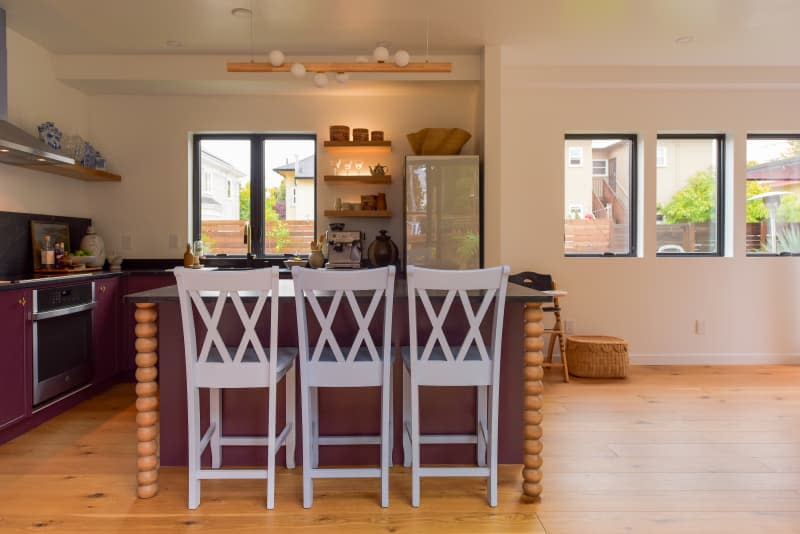 Barstools seen in neutral toned kitchen and living space.