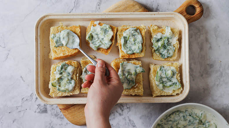 Spreading tzatziki on the buns