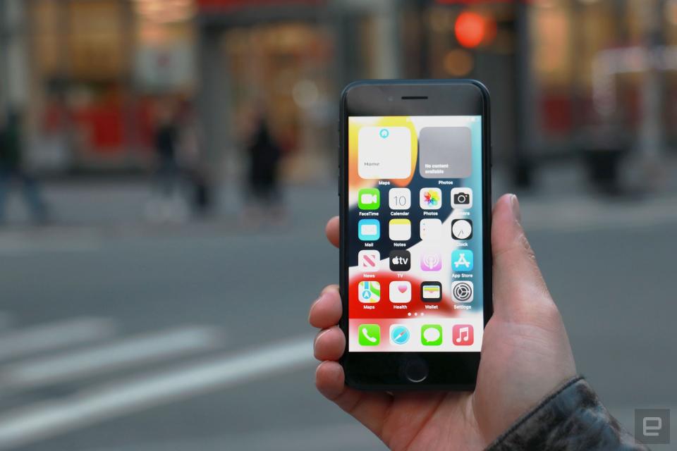 <p>The iPhone SE (2022) held in mid-air in front of a store.</p>
