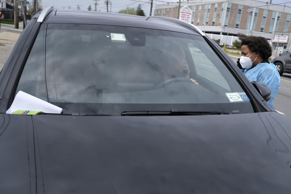 Dr. Jacqueline Delmont, Chief Medical Officer of Somos Community Care, right, gives Ana Olivero some details about her coronavirus antibody test after she came to be tested at a drive-through testing site in Hempstead, N.Y., Tuesday, April 14, 2020. The paperwork and armband on Olivero's windshield says that she trusted positive for antibodies and may therefore have some immunity to the coronavirus. (AP Photo/Seth Wenig)