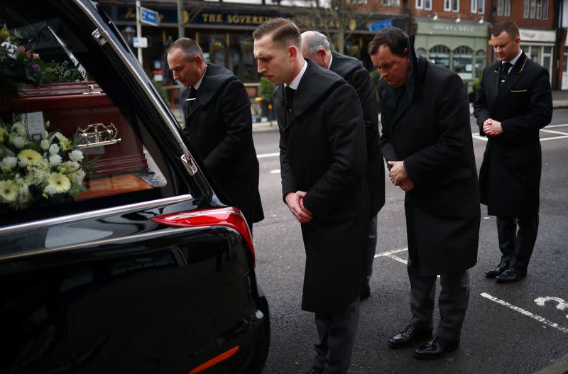 Pallbearers from W. Uden & Sons Family Funeral Directors bow their heads to a coffin during a funeral service in Bromley, amid the coronavirus disease (COVID-19) pandemic, in south east London