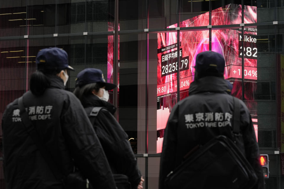 Tokyo fire department personnel wait for a traffic light, standing by monitors showing Japan's Nikkei 225 index at a securities firm in Tokyo, Thursday, Dec. 1, 2022. Shares have advanced in Asia after a rally on Wall Street spurred by the Federal Reserve chair's comments on easing the pace of interest rate hikes to tame inflation.((AP Photo/Hiro Komae)