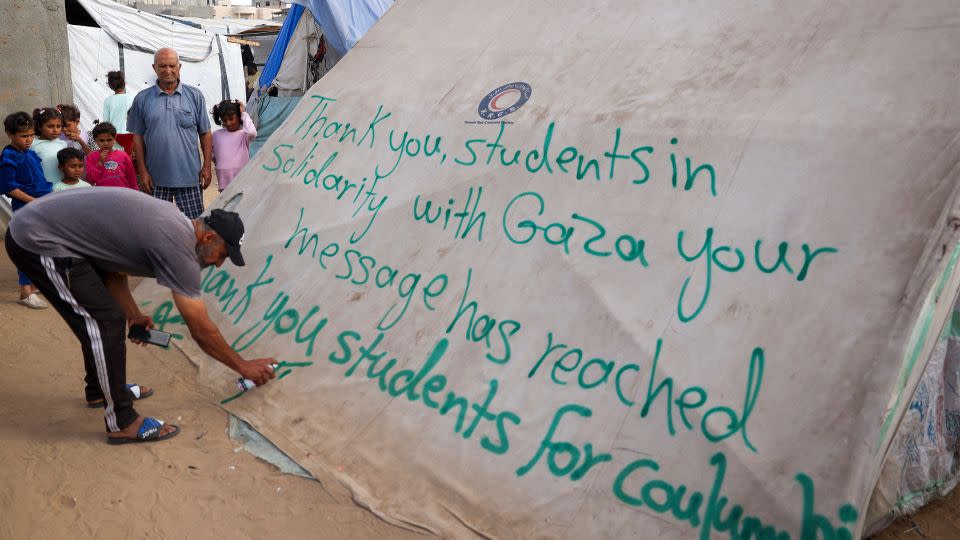 A man in Rafah, Gaza, writes a message of thanks to student protesters in the US on April 27, 2024. - AFP/Getty Images