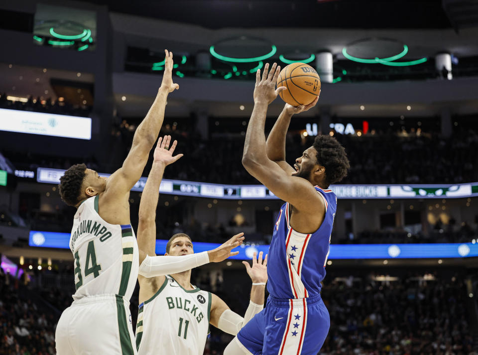 Philadelphia 76ers center Joel Embiid, right, shoots over Milwaukee Bucks forward Giannis Antetokounmpo (34) during the first half of an NBA basketball game Sunday, April 2, 2023, in Milwaukee. (AP Photo/Jeffrey Phelps)