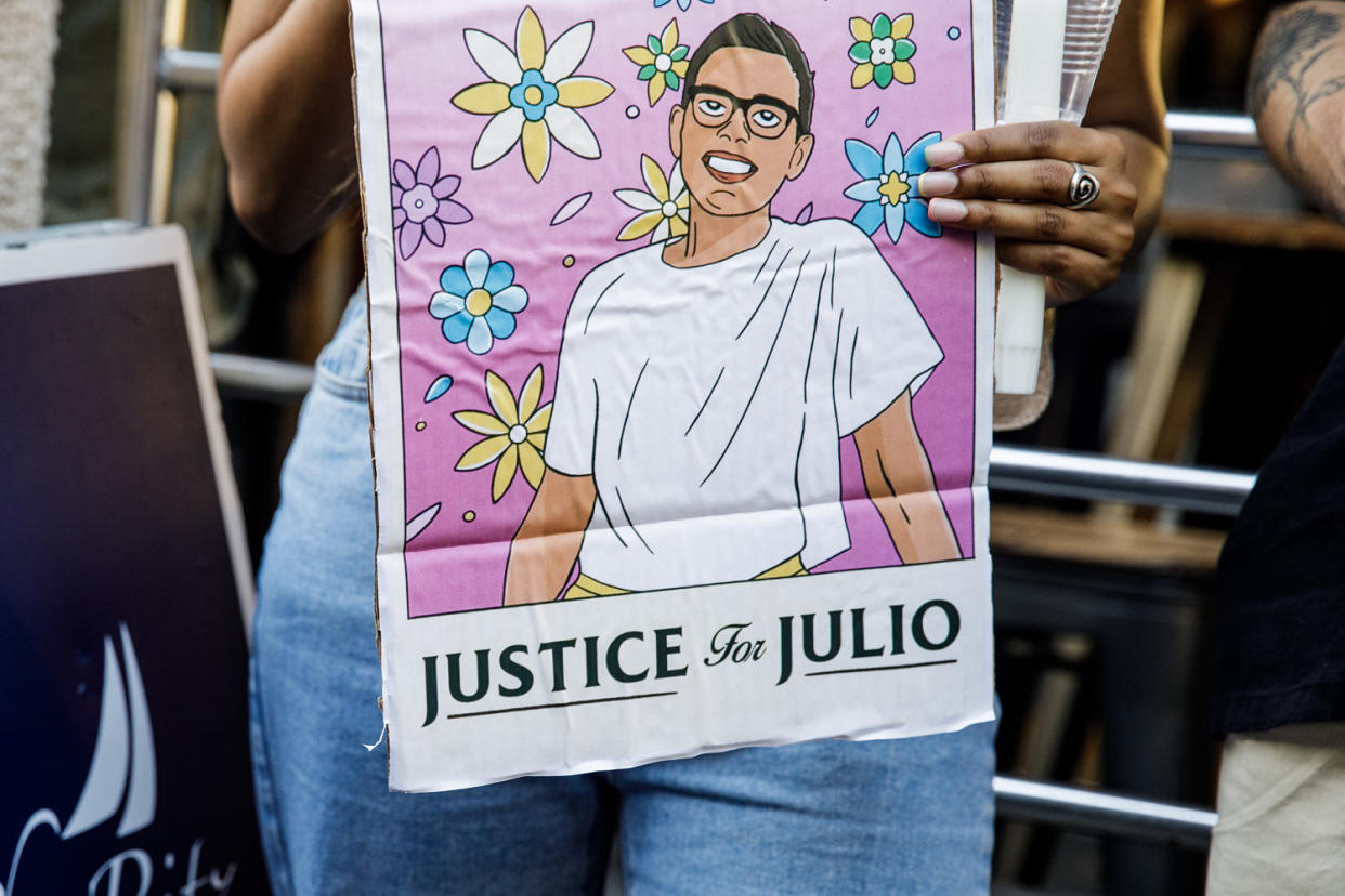 A person hold signs a sign with an illustration of Julio Ramirez (Julius Constantine Motal /. NBC News)