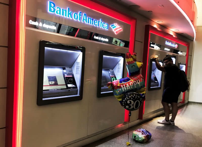 FILE PHOTO: A man uses an ATM machine next an inflatable plastic balloon inside a Bank of America branch in Times Square in New York