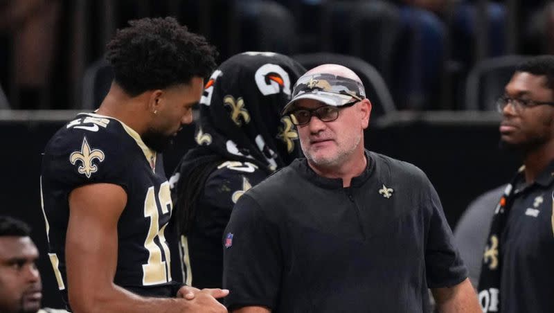 New Orleans Saints “athletic engineer” Matt Rhea, right, talks with Saints receiver Chris Olave on the sidelines during game in New Orleans.
