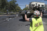 A protester taunts police driving past in an armored vehicle in Santiago, Chile, Monday, Oct. 21, 2019. Hundreds of protesters are defying an emergency decree to confront police in Chile's capital, continuing disturbances that have left at least 11 dead and led the president to say the country is "at war." (AP Photo/Luis Hidalgo)