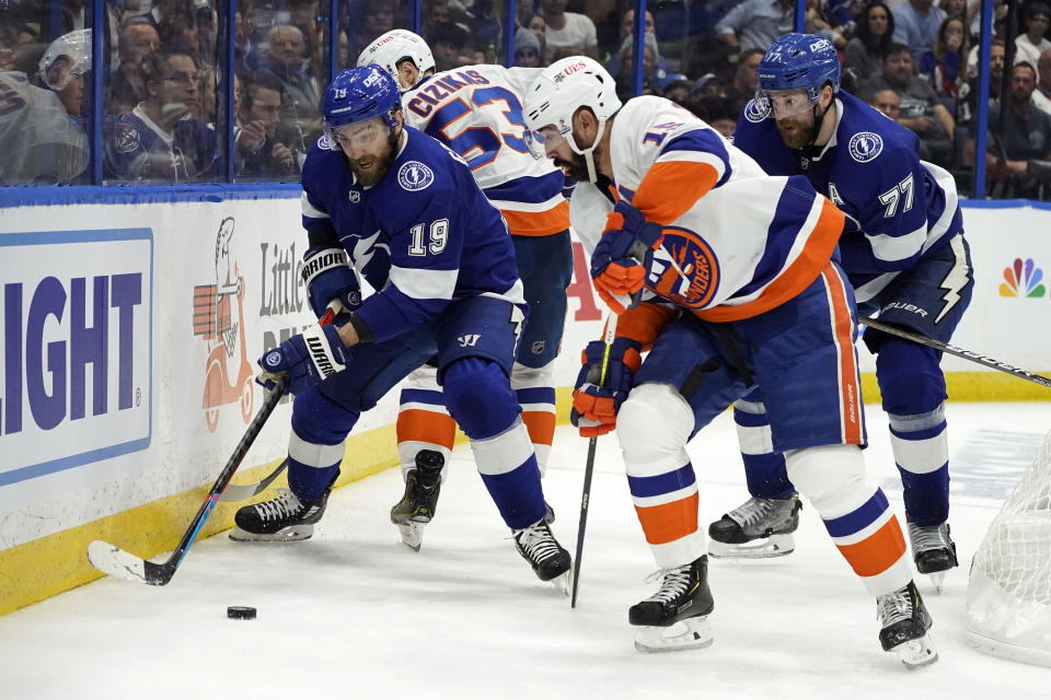 Tampa Bay Lightning center Barclay Goodrow (19) moves the puck past New York Islanders center Casey Cizikas (53) and right wing Cal Clutterbuck, front right, during the third period in Game 7 of an NHL hockey Stanley Cup semifinal playoff series Friday, June 25, 2021, in Tampa, Fla. (AP Photo/Chris O'Meara)