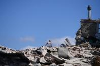 A man sits on top of rubble in Amatrice on August 24, 2016