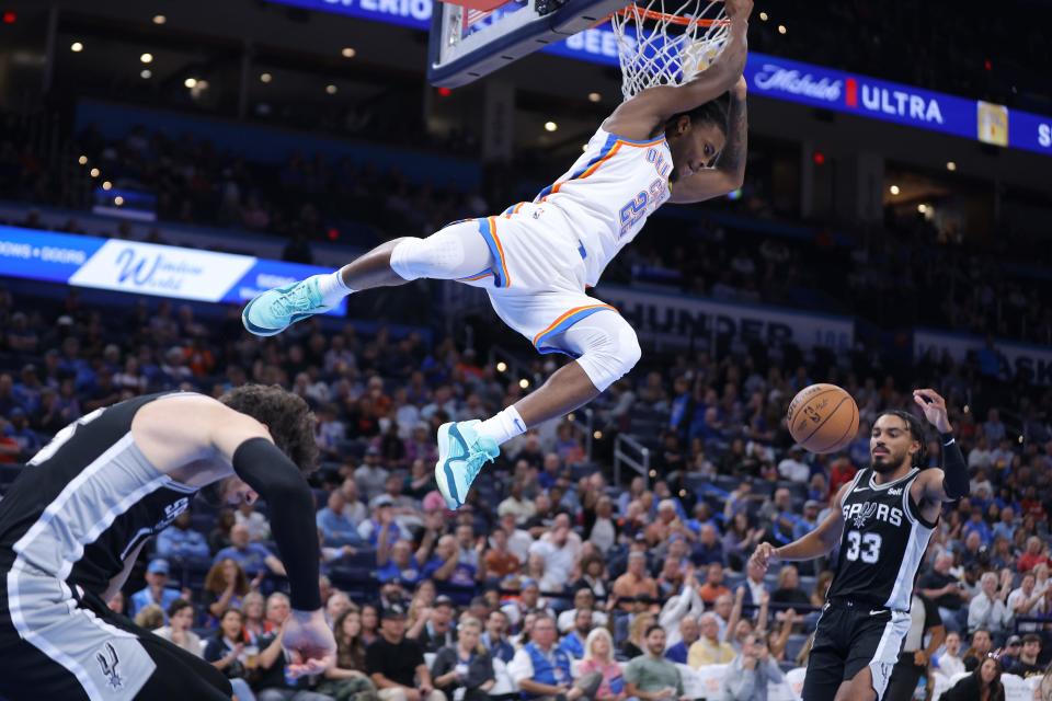 Oklahoma City Thunder guard Cason Wallace (22) hangs on the rim after a dunk during an NBA preseason basketball game between the Oklahoma City Thunder and the San Antonio Spurs at Paycom Center in Oklahoma City, Monday, Oct. 9, 2023.