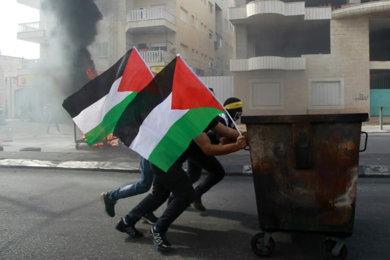 Palestinian protesters push a waste container during clashes with Israeli security forces on October 13, 2015 in the West Bank city of Bethlehem