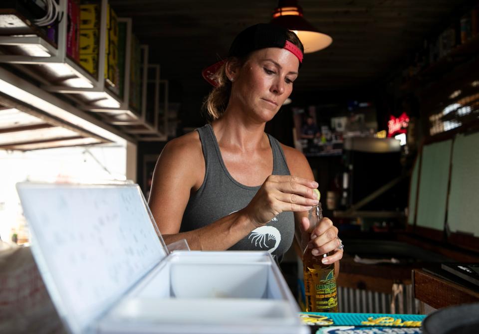 Lisa Lahners, owner of The RUDE Shrimp Company on Fort Myers Beach, gets a beer for a customer on Tuesday, Sept. 12, 2023.