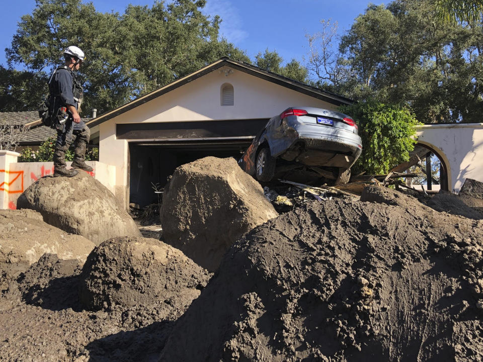 FILE - In this Saturday, Jan. 13, 2018 photo provided by the Santa Barbara County Fire Department, Capt. John Pepper, Fresno Fire Department, and Rescue Squad Leader RTF-5, searches homes off East Valley Road in Montecito, Calif. According to a study published in Science Advances on Friday, April 1, 2022, a one-two punch of nasty wildfires followed by heavy downpours, triggering flooding and mudslides, will strike the U.S. West far more often in a warming-hopped world, becoming a frequent occurrence. (Mike Eliason/Santa Barbara County Fire Department via AP, File)