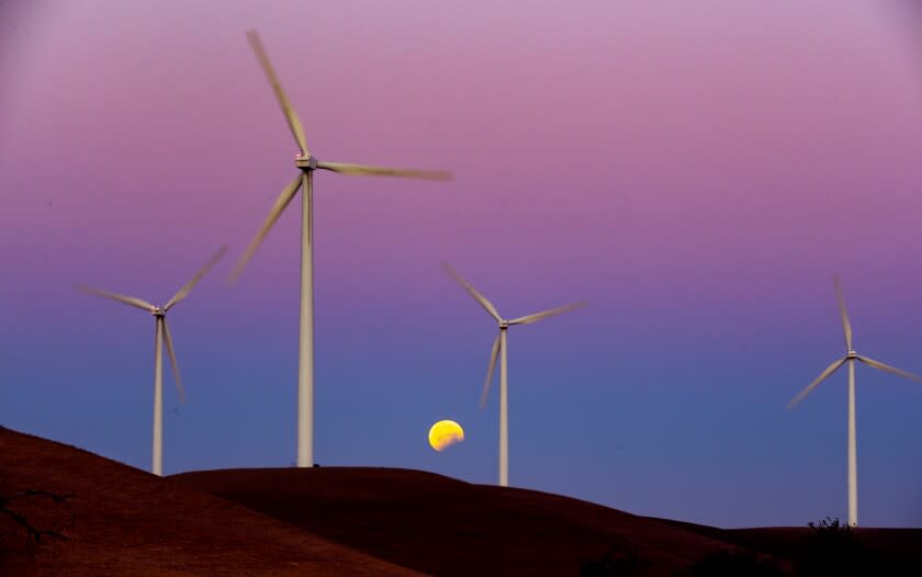 RIO VISTA, CALIF. -- WEDNESDAY, MAY 26, 2021: Turbines spin as the Blood Moon lunar eclipse sets behind the towers on the Shiloh II wind farm in the Montezuma Hills near Bird's Landing, Calif., on May 26, 2021. (Brian van der Brug / Los Angeles Times)