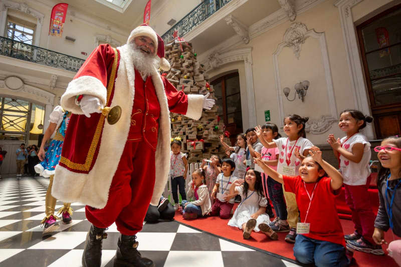 A man with Santa Claus costumes hands presents to children during a solidarity campaign ahead of Christmas Day. Francisco Vicencio Salinas/Agencia Uno/dpa