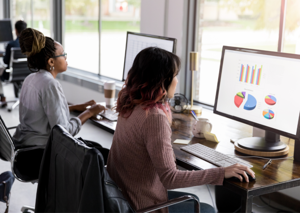 Two people work at desktop computers in an office.