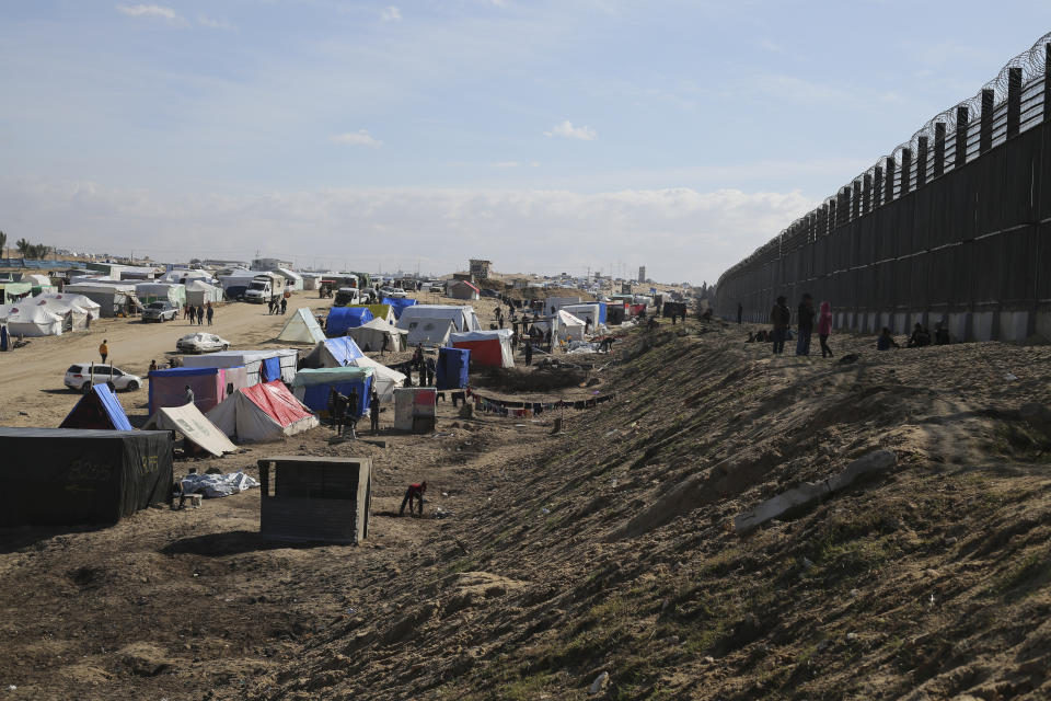 Palestinians displaced by the Israel air and ground offensive on the Gaza Striptake shelter near the border fence with Egypt in Rafah, Wednesday, Jan. 24, 2024. (AP Photo/Hatem Ali)