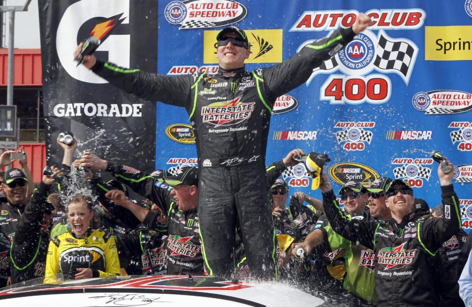 Kyle Busch, center, celebrates, as the team drenches his wife, Samantha Busch, left, in victory circle after winning the NASCAR Sprint Series auto race in Fontana, Calif., Sunday, March 23, 2014. (AP Photo/Alex Gallardo)