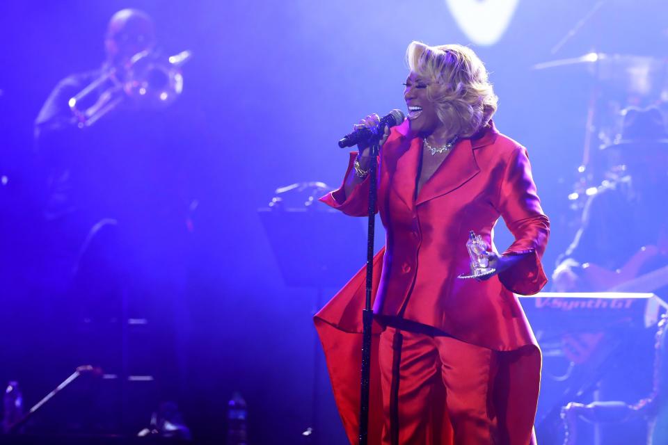 Patti LaBelle in a red suit singing into a microphone