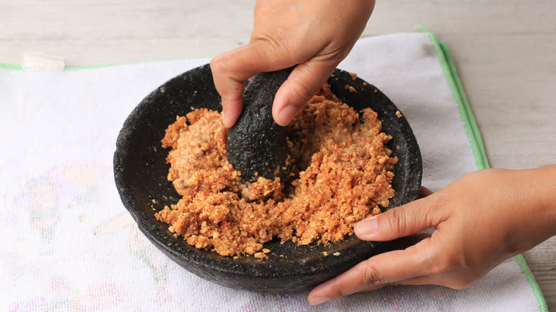 Person grinding peanuts in mortar and pestle