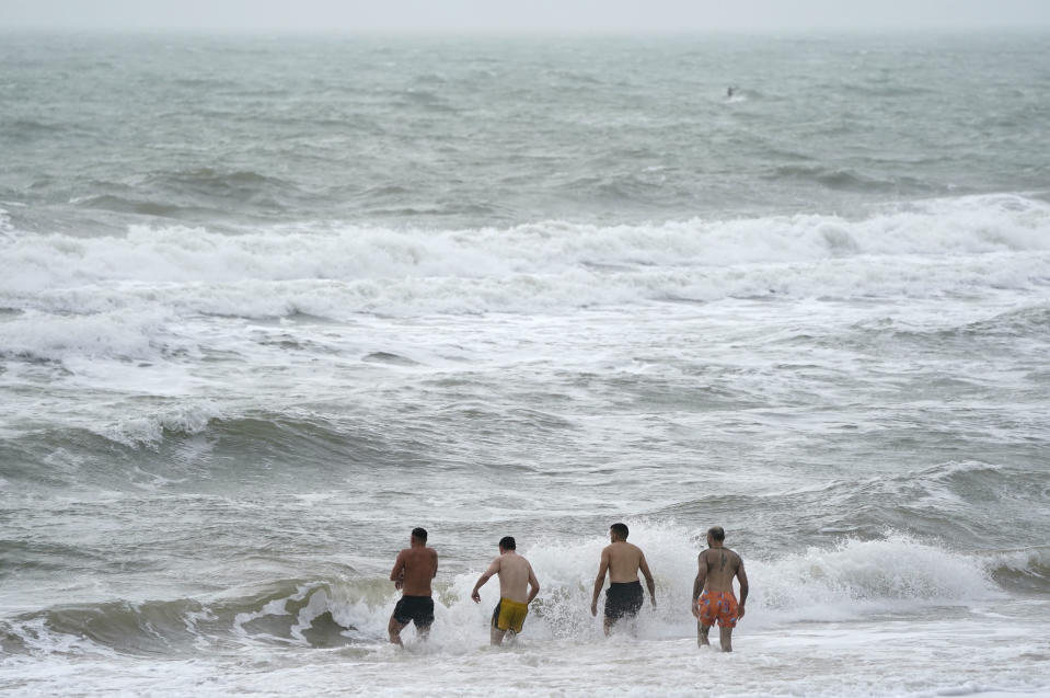 People enter in the sea at Boscombe beach in Dorset, England, Sunday, Jan. 21, 2024, ahead of an expected Storm Isha. (Andrew Matthews/PA via AP)