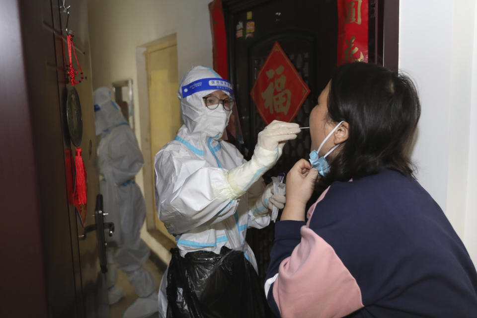 A medical worker takes swab sample from a residents during a door-to-door Covid-19 screening in Zhengzhou in central China's Henan province Tuesday, Nov. 1, 2022. Access to an industrial zone in the central Chinese city of Zhengzhou was suspended Wednesday after the city reported 64 coronavirus cases and workers who assemble Apple Inc. iPhones left their factory in the zone following outbreaks. (Chinatopix Via AP)