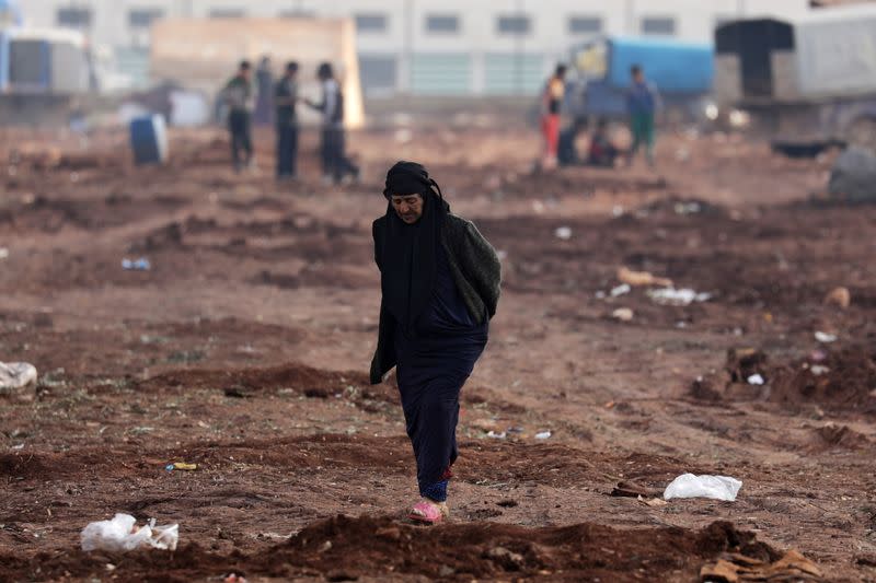 An internally displaced woman walks at a makeshift camp in Azaz