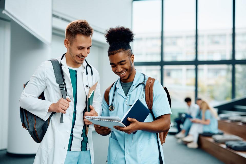 Two people in medical coats commiserating in a hallway.