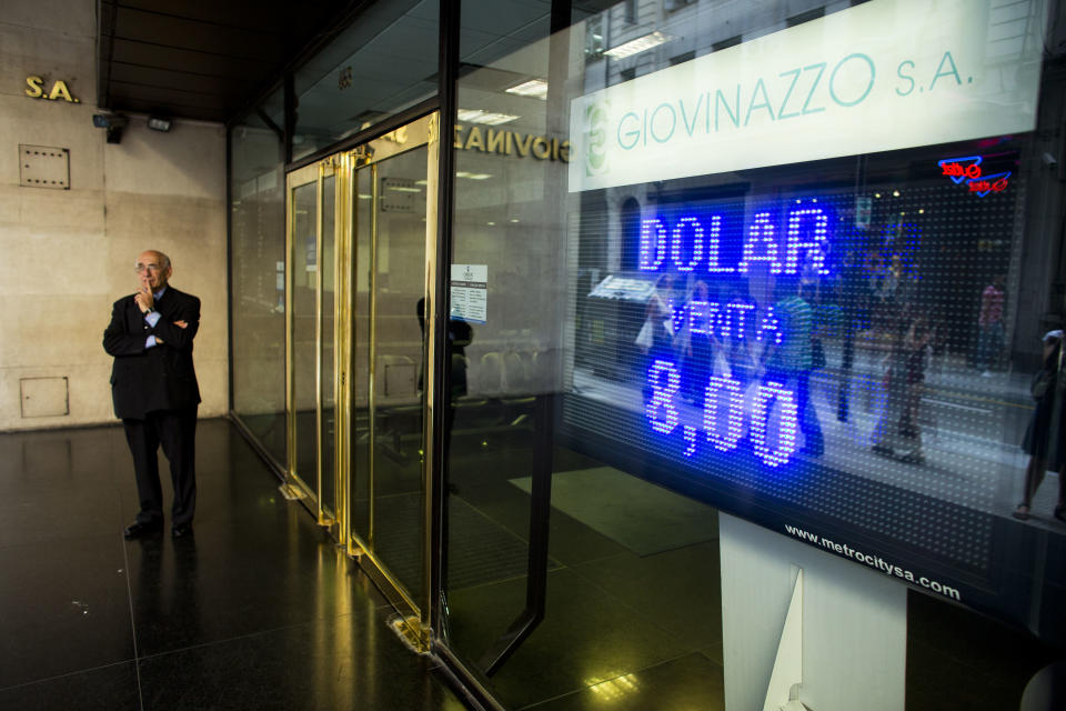 A man stands next to a sign indicating the exchange rate between the Argentine peso and the U.S. dollar in Buenos Aires, Argentina, Thursday, Jan. 23, 2014. The peso has plunged just over 17 percent in the last two days against the U.S. dollar, and economic analysts expect inflation to hit 30 percent this year. (AP Photo/Victor R. Caivano)