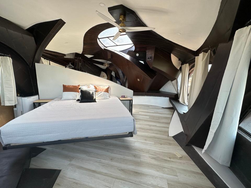 Bedroom with white sheets and a white and dark-brown curvy pattern on walls and ceiling