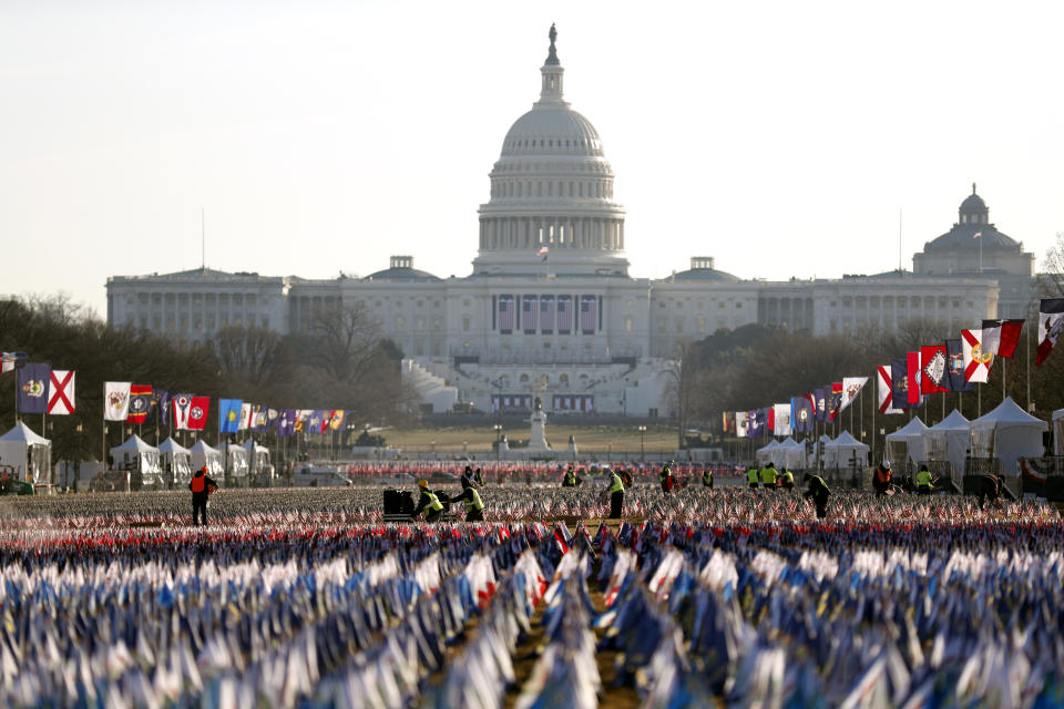 Workers begin to remove a display of flags on the National Mall one day after the inauguration of President Joe Biden, Thursday, Jan. 21, 2021, in Washington. (AP Photo/Rebecca Blackwell)