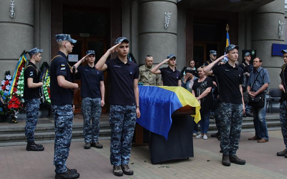  Relatives and comrades of Lieutenant Colonel Sergiy Derduga, Commander of the Ukrainian 18th Marine Battalion, stand by his coffin during his funeral ceremony in Odesa, on June 6, 2022. - Oleksandr Gimanov/AFP