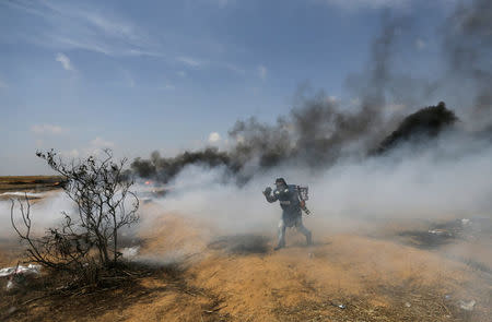 A photojournalist runs during clashes between Israeli troops and Palestinians at a protest where Palestinians demand the right to return to their homeland, at the Israel-Gaza border in the southern Gaza Strip, April 27, 2018. REUTERS/Ibraheem Abu Mustafa