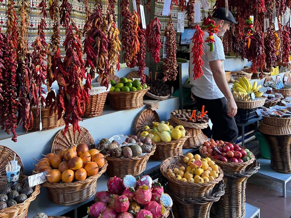 Fruit in baskets at a market, with spices hanging from the ceiling.