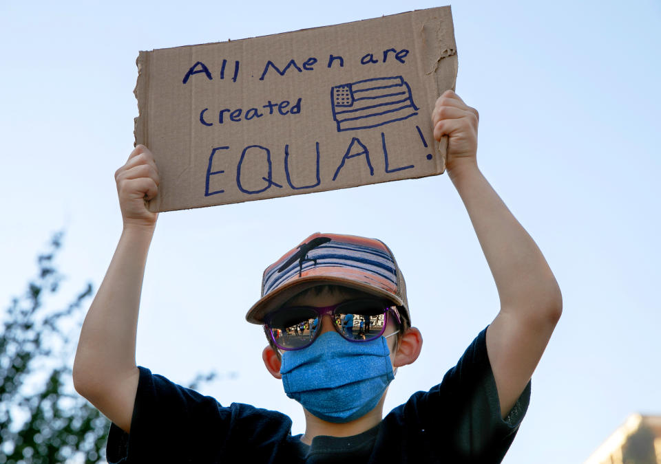 FILE - A boy holds a sign saying "All men are created equal," as he attends a protest on June 7, 2020, near the White House in Washington, over the death of George Floyd, a black man who was in police custody in Minneapolis. “All men are created equal.” Few words in American history are invoked as often as the preamble to the Declaration of Independence, published nearly 250 years ago, and few more difficult to define. (AP Photo/Jacquelyn Martin, File)