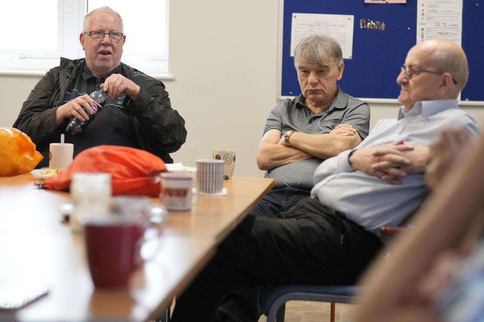 Barrie Stradling, left speaks at the weekly lunch meeting of some 20 retired men at the Tredegar community centre in Bow, in east London, Thursday, May 16, 2024. Passing around plates of cheese and crackers and slices of crème cake, they drank steaming coffee and tea. What they wanted was a chance to vent about the problems facing Britain and the fact that no one is listening to them as the country prepares for an election later this year. (AP Photo/Alastair Grant)