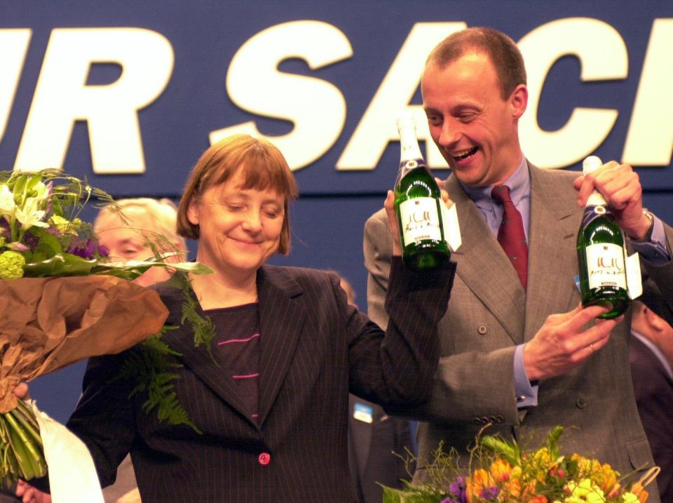 Nordrhein-Westfalen, Essen: Nach ihrer Wahl zur neuen Vorsitzenden der CDU am 10.04.2000, bekommt Angela Merkel beim CDU-Bundesparteitag vom Unionsfraktionsvorsitzenden Friedrich Merz zwei Flaschen Sekt überreicht. (Bild: dpa/Michael Jung)